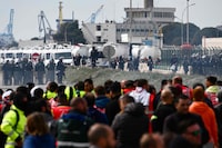 French riot police look on as oil worker gather outside the refinery after the government announced the first requisition of oil workers since the beginning of strikes against pension reform, at the Fos-sur-Mer fuel depot, southeastern France, on March 21, 2023, a decision that could inflame tensions in an inflammatory political context. - The French prime minister's government on March 20, survived two no-confidence motions over its decision to bypass parliament and impose a controversial pension reform, which includes raising the retirement age from 62 to 64. (Photo by CHRISTOPHE SIMON / AFP) (Photo by CHRISTOPHE SIMON/AFP via Getty Images)