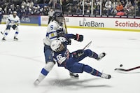 United States forward Kendall Coyne Schofield (26) is tripped by Finland defensewoman Siiri Yrjola (5) during the second period in the semifinals at the IIHF women's world hockey championships in Utica, N.Y., Saturday, April 13, 2024. Yrjola was called for holding on the play. (AP Photo/Adrian Kraus)
