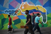 TOPSHOT - People walk by a mural campaigning for a referendum to ask Venezuelans to consider annexing the Guyana-administered region of Essequibo, in 23 de Enero neighbourhood in Caracas on November 28, 2023. Venezuela is scheduled to hold a controversial referendum on December 3, to annex a disputed oil-rich territory administered by neighbouring Guyana. The government of Nicolas Maduro has organized the poll to ask Venezuelans to consider annexing the Essequibo region, which makes up two-thirds of tiny Guyana but is claimed by Caracas. (Photo by Federico PARRA / AFP) (Photo by FEDERICO PARRA/AFP via Getty Images)