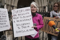 Protester Trudi Warner holding a sign outside the Royal Courts of Justice in London, following a High Court ruling in London, Monday, April 22, 2024. A London judge says a climate protester who could have faced up to two years in prison for holding a sign outside a courthouse reminding jurors of their right to acquit defendants should not be charged with contempt of court. High Court Justice Pushpinder Saini said Monday that Trudi Warner's act was not a crime because jurors can reach a verdict based on their conscience. (Lucy North/PA via AP)