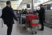 Airline staff manage holidaymakers and travellers as they queue at a check-in desk in the departure hall of Terminal 2 at London Heathrow Airport in west London, on April 6, 2022. - British Airways on Wednesday cancelled 78 flights scheduled to land at, or take-off from, Heathrow Airport on Wednesday as staff shortages due to the Covid-19 pandemic continue to disrupt the aviation industry. (Photo by JUSTIN TALLIS / AFP) (Photo by JUSTIN TALLIS/AFP via Getty Images)
