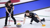 Team Walker/Muyres third Kirk Muyres, right, makes a shot as skip Laura Walker sweeps while they play Team Einarson/Gushue at the Canadian Mixed Doubles Curling Championship in Calgary, Alta., Wednesday, March 24, 2021.THE CANADIAN PRESS/Jeff McIntosh