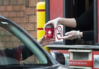 A Tim Hortons employee hands out coffee from a drive-through window to a customer in Mississauga, Ont., on Tuesday, March 17, 2020. The new executive chairman of Restaurant Brands International Inc. has laid out a sweeping vision for the fast-food giant's four chains, with plans to borrow from his winning playbook as CEO of Domino's Pizza. THE CANADIAN PRESS/Nathan Denette