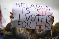 FILE - A woman holds a placard during an opposition rally to protest the official presidential election results in Minsk, Belarus, on Oct. 25, 2020. Belarusians will cast ballots Sunday in tightly controlled parliamentary and local elections that are set to cement an authoritarian leader's rule, despite calls for a boycott by an opposition leader who described the balloting as a "senseless farce." (AP Photo, File)