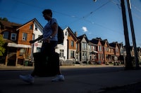 A person walks by a row of houses in Toronto on Tuesday July 12, 2022. Strong demand for rentals and a shortage of homes is leading to soaring rental costs that are only making saving up for a home even more difficult.THE CANADIAN PRESS/Cole Burston