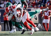 Saskatchewan Roughriders linebacker Larry Dean, centre, brings down Calgary Stampeders receiver Malik Henry during first half CFL football action in Calgary, Alta., Saturday, June 24, 2023. THE CANADIAN PRESS/Jeff McIntosh