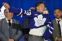 Easton Cowan puts on a Toronto Maple Leafs jersey after being picked by the team during the first round of the NHL hockey draft Wednesday, June 28, 2023, in Nashville, Tenn. The Leafs have signed Cowan to a three-year, entry-level contract.THE CANADIAN PRESS/AP-George Walker IV