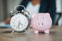 Piggy bank, clock or business person writing financial info or budget for savings or investment in office. Time management, reminder blur or professional worker with notes for insurance or taxes