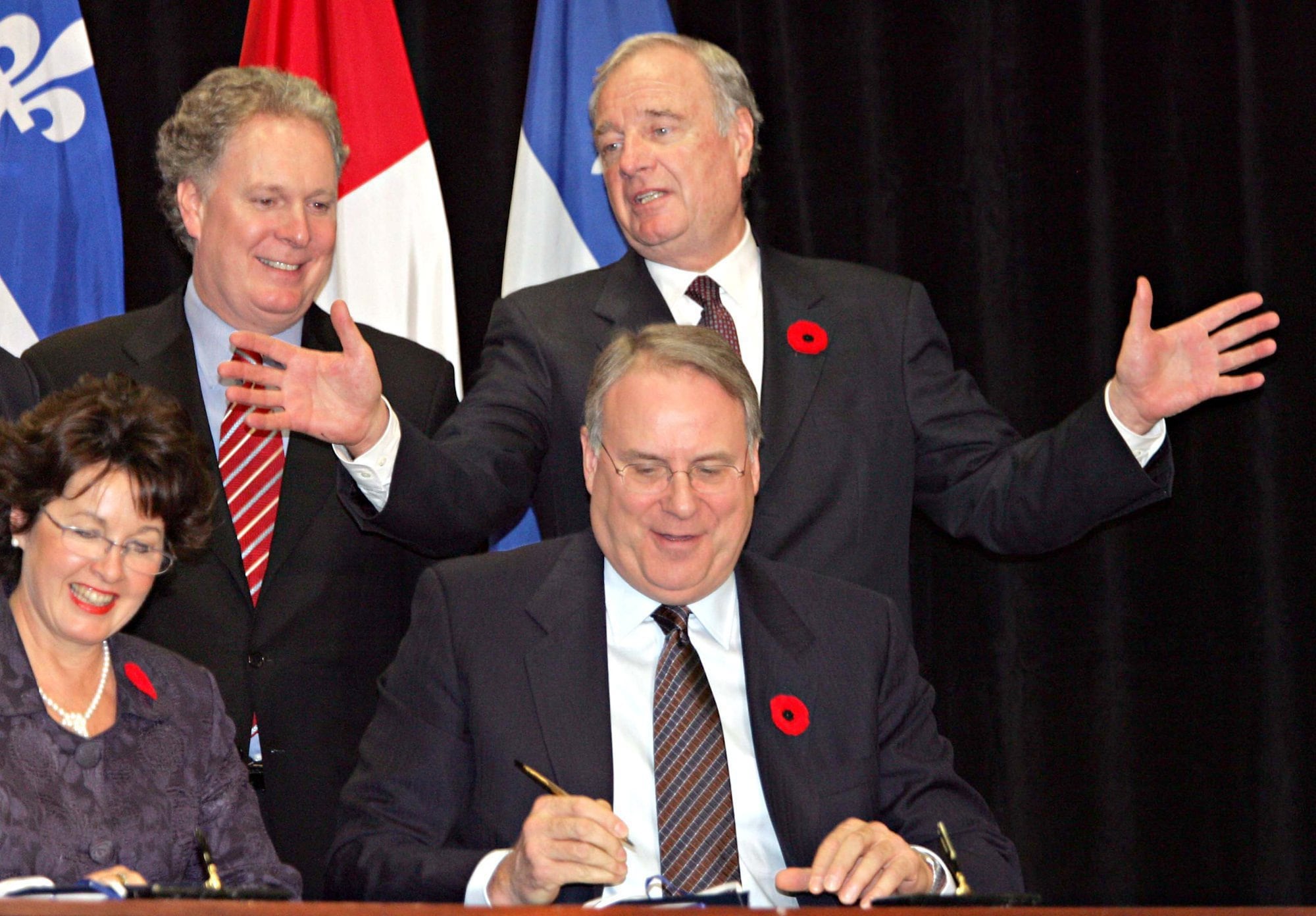 Prime Minister Paul Martin gestures to Quebec Premier Jean Charest as social development Minister Ken Dryden and Carole Theberge sign a child care deal in Montreal in October, 2005.