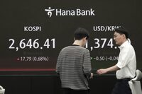 Currency traders pass by the screen showing the Korea Composite Stock Price Index (KOSPI), left, and the foreign exchange rate between U.S. dollar and South Korean won at the foreign exchange dealing room of the KEB Hana Bank headquarters in Seoul, South Korea, Friday, April 26, 2024. Asian shares mostly rose Friday despite worries about the economic outlook and inflation in the U.S. and the rest of the world. (AP Photo/Ahn Young-joon)
