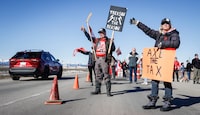 Anti-carbon levy protesters wave signs and chant slogans as they block a westbound lane of the Trans-Canada highway near Cochrane, Alta., Monday, April 1, 2024.THE CANADIAN PRESS/Jeff McIntosh