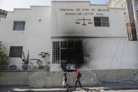 Pedestrians walk past a court building that was set on fire by gangs moments before in the Delmas 28 neighborhood of Port-au-Prince, Haiti, Wednesday, March 6, 2024. (AP Photo/Odelyn Joseph)