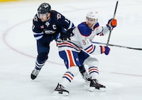 Winnipeg Jets' Adam Lowry (17) and Edmonton Oilers' Connor McDavid (97) collide during first period NHL action in Winnipeg on Thursday, November 30, 2023. THE CANADIAN PRESS/John Woods