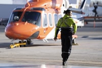 An arbitrator has ruled that air ambulance service Ornge must pay its paramedics more money after wage restraint legislation known as Bill 124 was struck down. A medic walks past an ORNGE air ambulance service helicopter at their base at Billy Bishop Airport in Toronto on Tuesday, December 13, 2022. THE CANADIAN PRESS/Chris Young