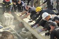 In this photo provided by the National Police of Ukraine, emergency services and policemen work to save an injured police officer from under the rubble following a Russian attack in Kryvyi Rih, Ukraine, Friday, Sept. 8, 2023. (National Police of Ukraine via AP)