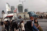 People stand at a bus stop on Southwark Bridge, backdropped by skyscrapers in the the City of London, on November 10, 2023. Britain's economy stagnated in the third quarter, official data showed Friday, weighed down by elevated inflation and interest-rate hikes. (Photo by Daniel LEAL / AFP) (Photo by DANIEL LEAL/AFP via Getty Images)
