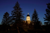 The Maine State House is seen at sunrise, Wednesday, Dec. 2, 2020, in Augusta, Maine. Maine Republicans are angry about a proposal by the Democratic-led Legislature's spending committee that would draw money from the highway fund, reduce a tax break for seniors and eliminate much of the $107 million the governor wanted to set aside in anticipation of slowing revenues. (AP Photo/Robert F. Bukaty)