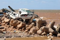 TOPSHOT - Cars are piled up atop wave breakers and the rubble of a building destroyed in flash floods after the Mediterranean storm "Daniel" hit Libya's eastern city of Derna, on September 14, 2023. A global aid effort for Libya gathered pace on September 14 after a tsunami-sized flash flood killed at least 4,000 people, with thousands more missing, a death toll the UN blamed in part on the legacy of years of war and chaos. (Photo by Abdullah DOMA / AFP) (Photo by ABDULLAH DOMA/AFP via Getty Images) *** BESTPIX ***