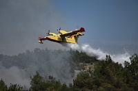 A Canadair amphibious aircraft, drops water over wildfires spreading in Dadia forest, one of the most important areas in Europe for birds of prey,  as it rages in Dadia, near Alexandroupoli, north Greece, on August 24, 2023. Hundreds of firefighters in Greece struggled Thursday to tame major wildfires burning for a sixth day, leaving 20 dead and prompting growing outrage among stricken residents. (Photo by Sakis MITROLIDIS / AFP) (Photo by SAKIS MITROLIDIS/AFP via Getty Images)