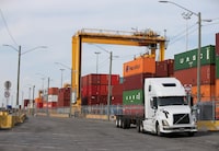FILE PHOTO: A truck moves past stacked shipping containers at the Port of Montreal in Montreal, Quebec, Canada, May 17, 2021.  REUTERS/Christinne Muschi/File Photo