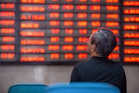 An investor looks at screens showing stock market movements at a securities company in Nanjing in China's eastern Jiangsu province on July 6, 2020.