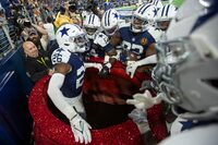 Dallas Cowboys cornerback DaRon Bland (26) celebrates in the Salvation Army Red Kettle with teammates after running back an interception for a touchdown during an NFL football game against the Washington Commanders, Thursday, Nov. 23, 2023, in Arlington, Texas. Dallas won 45-10. (AP Photo/Brandon Wade)