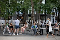 A woman walks by wearing a mask as people are seen at outdoor seating in Yorkville in Toronto on June 26, 2020. The Gordon Lightfoot who first performed in Toronto's Yorkville, what's now one of Canada's ritziest neighbourhoods, is not the Gordon Lightfoot we know today. THE CANADIAN PRESS/Cole Burston