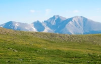 This July 17, 2016, photo shows Longs Peak towering over alpine tundra in Rocky Mountain National Park, Colo. A draft report released Wednesday, April 10, 2019, said harmful nitrogen pollution is still drifting onto fragile high-elevation ecosystems in the park from Colorado highways, power plants and livestock operations. The report, released by the Colorado Department of Public Health and Environment, the U.S. Environmental Protection Agency and the National Park Service, recommended against activating a contingency plan to reduce pollution, saying nitrogen levels did not increase much in the previous decade. (AP Photo/Dan Elliott)