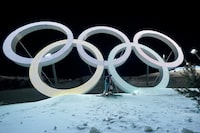 Switzerland's Marco Tade takes pictures by the Olympic Rings during a training for the men's freestyle moguls skiing competition ahead of the 2022 Winter Olympics, Tuesday, Feb. 1, 2022, in Zhangjiakou, China. (AP Photo/Gregory Bull)