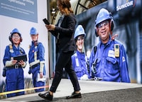 Delegates walks past an image of oil workers at the World Petroleum Congress  in Calgary, Monday, Sept. 18, 2023.THE CANADIAN PRESS/Jeff McIntosh