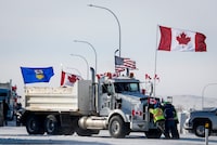 Drivers work to move a gravel truck after a breakthrough to resolve the impasse at a protest blockade at the United States border in Coutts, Alta., Wednesday, Feb. 2, 2022. Trucks and other vehicles have begun clearing two lanes -- one going north and one going south. THE CANADIAN PRESS/Jeff McIntosh