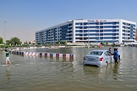 People recover a stranded car on a flooded street in Dubai following heavy rains on April 19, 2024. (Photo by Giuseppe CACACE / AFP) (Photo by GIUSEPPE CACACE/AFP via Getty Images)