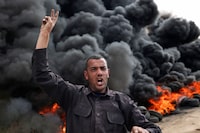 A Palestinian man gestures near burning tyres during a protest near the Israel-Gaza border east of Jabalia refugee camp, on February 23, 2023. - Israel and Palestinian militants traded air strikes and rocket fire in and around Gaza, a day after the deadliest Israeli army raid in the occupied West Bank in nearly 20 years. (Photo by MAHMUD HAMS / AFP) (Photo by MAHMUD HAMS/AFP via Getty Images)