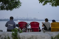 People sit along the waterfront at Humber Bay Park in Toronto on Wednesday, June 28, 2023. Toronto residents will be allowed to consume alcohol in a select number of parks across the city in the coming months after city council approved a time-limited pilot program. THE CANADIAN PRESS/Andrew Lahodynskyj