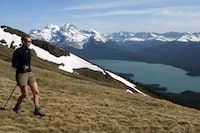 A hiker takes in the snow covered mountains surrounding Maligne Lake in Jasper National Park on June 22, 2002. Environmental groups are welcoming Parks Canada's buyout of two businesses in Jasper National Park's Tonquin Valley, a scenic destination also used by vanishing caribou herds. THE CANADIAN PRESS/Jonathan Hayward