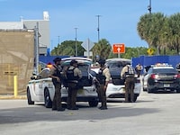 Police surround a Walmart in Florida City, Fla., about 25 miles (40 kilometers) southwest of Miami, Wednesday, July 19, 2023, after a shooting that left one person dead and another wounded. Three men are facing charges Thursday, July 20, after the shooting. (David Goodhue/Miami Herald via AP)