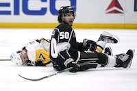 Pittsburgh Penguins center Sidney Crosby, left, lays on the ice after getting cross checked by Los Angeles Kings defenseman Mikey Anderson as defenseman Sean Durzi, right looks on during the third period of an NHL hockey game Saturday, Feb. 11, 2023, in Los Angeles. (AP Photo/Mark J. Terrill)