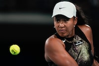 Naomi Osaka of Japan plays a backhand return to Caroline Garcia of France during their first round match at the Australian Open tennis championships at Melbourne Park, Melbourne, Australia, Monday, Jan. 15, 2024. (AP Photo/Louise Delmotte)
