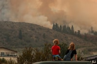FILE PHOTO: Locals gather to watch firefighting efforts amid heavy smoke from the Eagle Bluff wildfire, after it crossed the Canada-U.S. border from the state of Washington and prompted evacuation orders, in Osoyoos, British Columbia, Canada July 30, 2023. REUTERS/Jesse Winter/File Photo