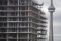 The CN Tower is seen in the distance behind a construction worker at a condominium development project in downtown Toronto on Oct 28, 2022. Fred Lum/The Globe and Mail. 