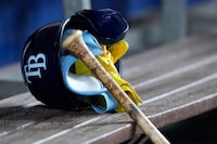 A batting helmet and gloves are shown on the bench alongside a bat during the first inning of a baseball game between the Miami Marlins and the Tampa Bay Rays, Wednesday, Aug. 30, 2023, in Miami. (AP Photo/Wilfredo Lee)