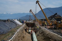 Workers lay pipe during construction of the Trans Mountain pipeline expansion on farmland, in Abbotsford, B.C., on Wednesday, May 3, 2023. The Canada Energy Regulator has issued its reasons for approving Trans Mountain's revised pipeline variance application. THE CANADIAN PRESS/Darryl Dyck