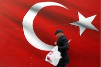 A man walks by a giant Turkish flag in Ankara, Turkey, Sunday, March 31, 2019. Turkish citizens have begun casting votes in municipal elections for mayors, local assembly representatives and neighborhood or village administrators that are seen as a barometer of Erdogan's popularity amid a sharp economic downturn. (AP Photo/Ali Unal)