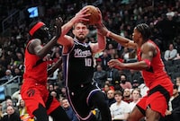 Sacramento Kings forward Domantas Sabonis (10) drives between Toronto Raptors forward Mouhamadou Gueye (left) and guard Jahmi'us Ramsey (right) during second half NBA basketball action in Toronto on Wednesday, March 20, 2024. THE CANADIAN PRESS/Nathan Denette