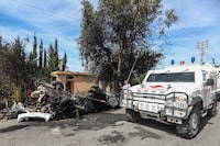 A U.N peacekeeper vehicle passes a destroyed car in the southern outskirts of Tyre, Lebanon, Wednesday, March 13, 2024. An Israeli drone strike Wednesday targeting a car in southern Lebanon near the coastal city of Tyre killed a member of Hamas and at least one other person.   (AP Photo/Mohammad Zaatari)