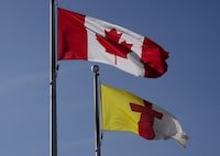 A Canadian flag flies beside an Nunavut flag in Iqaluit, Nunavut on July 31, 2019. A national policing program aimed at serving Indigenous communities in Canada is expanding to Nunavut. Through the First Nations and Inuit Policing Program, new RCMP officers will be hired across the territory over the next three years. THE CANADIAN PRESS/Sean Kilpatrick