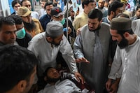 Haji Ghulam Ali (2nd R), governor of KP province greets an injured man in a hospital in Peshawar on July 30, 2023, after at least 44 people were killed and dozens more wounded by a suicide bombing at a political gathering of a leading Islamic party in northwest Pakistan. The blast targeted the Jamiat Ulema-e-Islam-F (JUI-F) party -- a government coalition partner led by an influential firebrand cleric -- as hundreds of supporters congregated under a canopy in the town of Khar, near the Afghan border. (Photo by Abdul Majeed AFP photographer / AFP) (Photo by ABDUL MAJEED AFP PHOTOGRAPHER/AFP via Getty Images)
