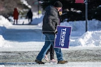 Supporters of former US President and 2024 presidential hopeful Donald Trump carry Trump placards as they brave the below zero temperatures to attend a rally in Indianola, Iowa, on January 14, 2024. (Photo by Jim WATSON / AFP) (Photo by JIM WATSON/AFP via Getty Images)