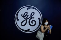 FILE PHOTO: A woman stands in front of a General Electric (GE) sign during World Artificial Intelligence Conference, following the coronavirus disease (COVID-19) outbreak, in Shanghai, China, September 1, 2022. REUTERS/Aly Song/File Photo