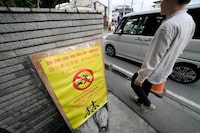 A notice for tourists across the use road from the Lawson convenience store, where a popular photo spot framing a picturesque view of Mount Fuji in the background Tuesday, April 30, 2024, at Fujikawaguchiko, Yamanashi Prefecture, central Japan. (AP Photo/Eugene Hoshiko)